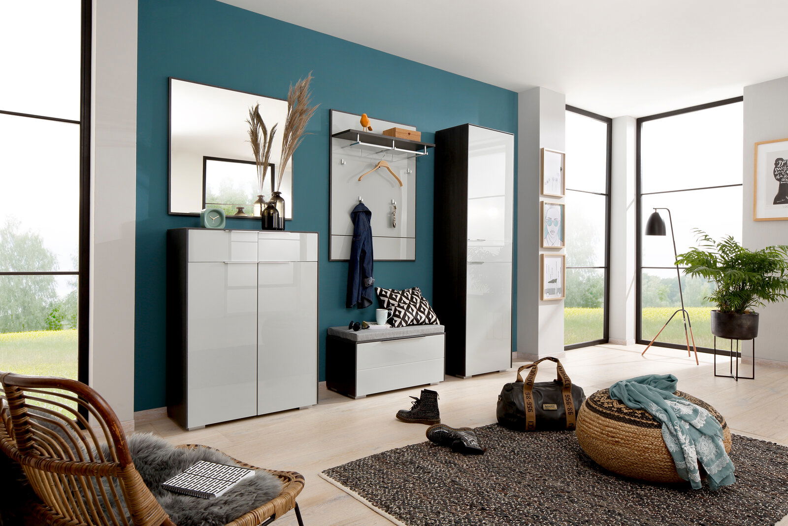 Moderne Garderobeneinrichtung mit Schuhschrank, Spiegel, Sitzbank und Garderobenpaneel in einem hellen Raum mit großen Fenstern, seitliche Perspektive.