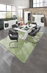 Moderne Esszimmermöbel in einem stilvollen Raum mit großen Fenstern, bestehend aus einem weißen Tisch, grauen Stühlen und weißen Vitrinen. Perspektive: Blick von oben auf den Essbereich.