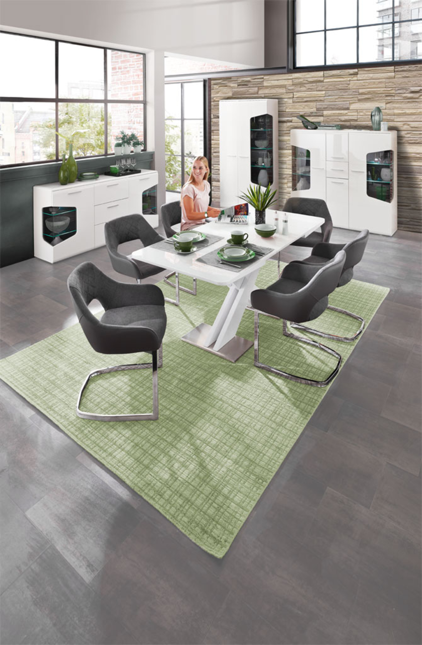 Moderne Esszimmermöbel in einem stilvollen Raum mit großen Fenstern, bestehend aus einem weißen Tisch, grauen Stühlen und weißen Vitrinen. Perspektive: Blick von oben auf den Essbereich.