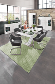 Moderne Esszimmermöbel in einem stilvollen Raum mit großen Fenstern, bestehend aus einem weißen Tisch, grauen Stühlen und weißen Vitrinen. Perspektive: Blick von oben auf den Essbereich.