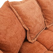 Nahaufnahme eines orangefarbenen Big-Sofas mit strukturierten Kissen.