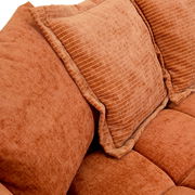 Nahaufnahme eines orangefarbenen Big-Sofas mit strukturierten Kissen.