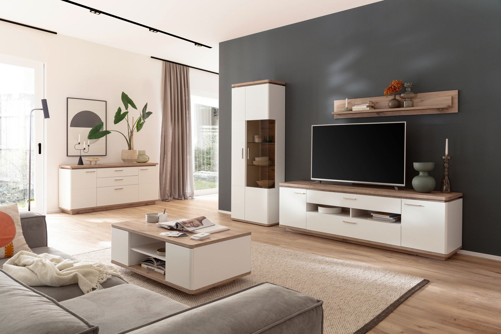 Moderne Wohnzimmer-Wandkombination in heller Holzoptik mit TV-Schrank, Vitrine und Wandregal, seitliche Perspektive