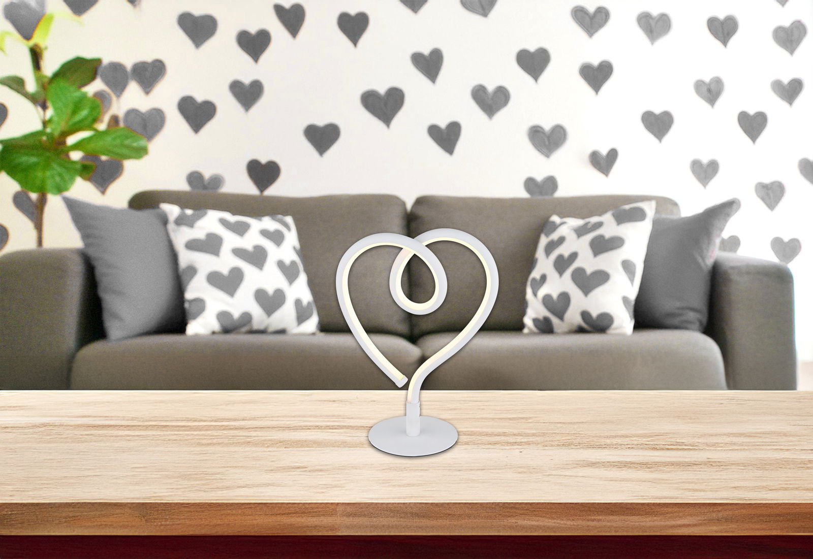 Globo Lighting LED-Tischleuchte AMORE LED-Tischleuchte in Herzform auf einem Tisch, im Hintergrund ein Sofa mit Herzmuster-Kissen, frontale Perspektive