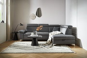 Graue Rundecke (L) in einem modernen Wohnzimmer, von vorne betrachtet, mit einem Beistelltisch und Dekorationen.