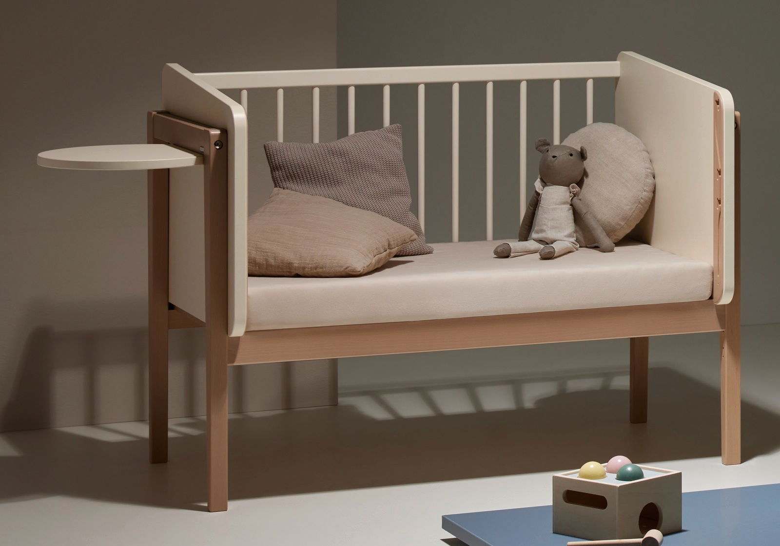 Kinderbett mit seitlichem Tischchen, Kissen und Stofftier, seitliche Perspektive