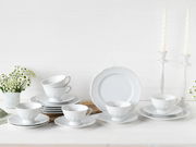 Elegantes 18-teiliges weißes Kaffeeservice mit Tassen, Untertassen und Tellern, stilvoll arrangiert auf einem Tisch mit Blumen und Kerzen, aus seitlicher Perspektive fotografiert.