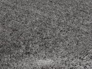 Nahaufnahme eines grauen Hochflor-Teppichs mit weicher, flauschiger Textur.