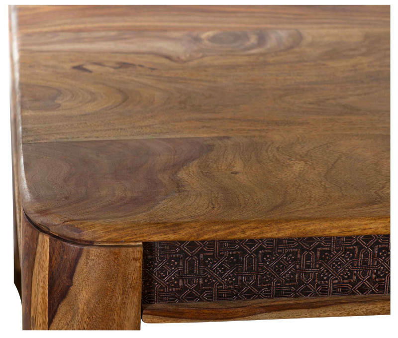 Nahaufnahme einer Ecke eines Esstisches aus Holz mit dekorativen Schnitzereien an der Seite, Perspektive von oben.