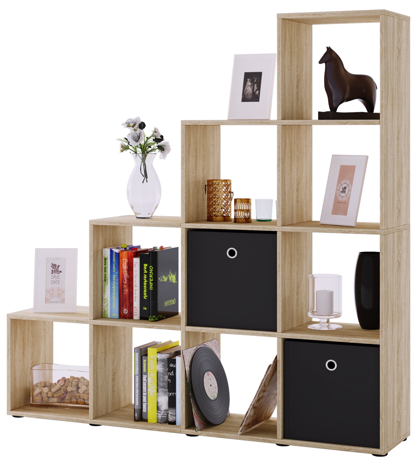 Stufenförmiges Regal aus heller Holzoptik mit offenen Fächern und drei schwarzen Stoffboxen, dekoriert mit Büchern, Bildern, Vase und Kerzen, freigestellt vor weißem Hintergrund, Frontansicht in leichter Schrägperspektive von links