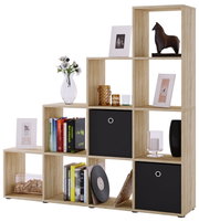 Stufenförmiges Regal aus heller Holzoptik mit offenen Fächern und drei schwarzen Stoffboxen, dekoriert mit Büchern, Bildern, Vase und Kerzen, freigestellt vor weißem Hintergrund, Frontansicht in leichter Schrägperspektive von links
