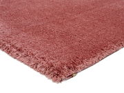 Nahaufnahme eines weichen, rosafarbenen Teppichs mit flauschiger Textur, gezeigt aus einer seitlichen Perspektive.