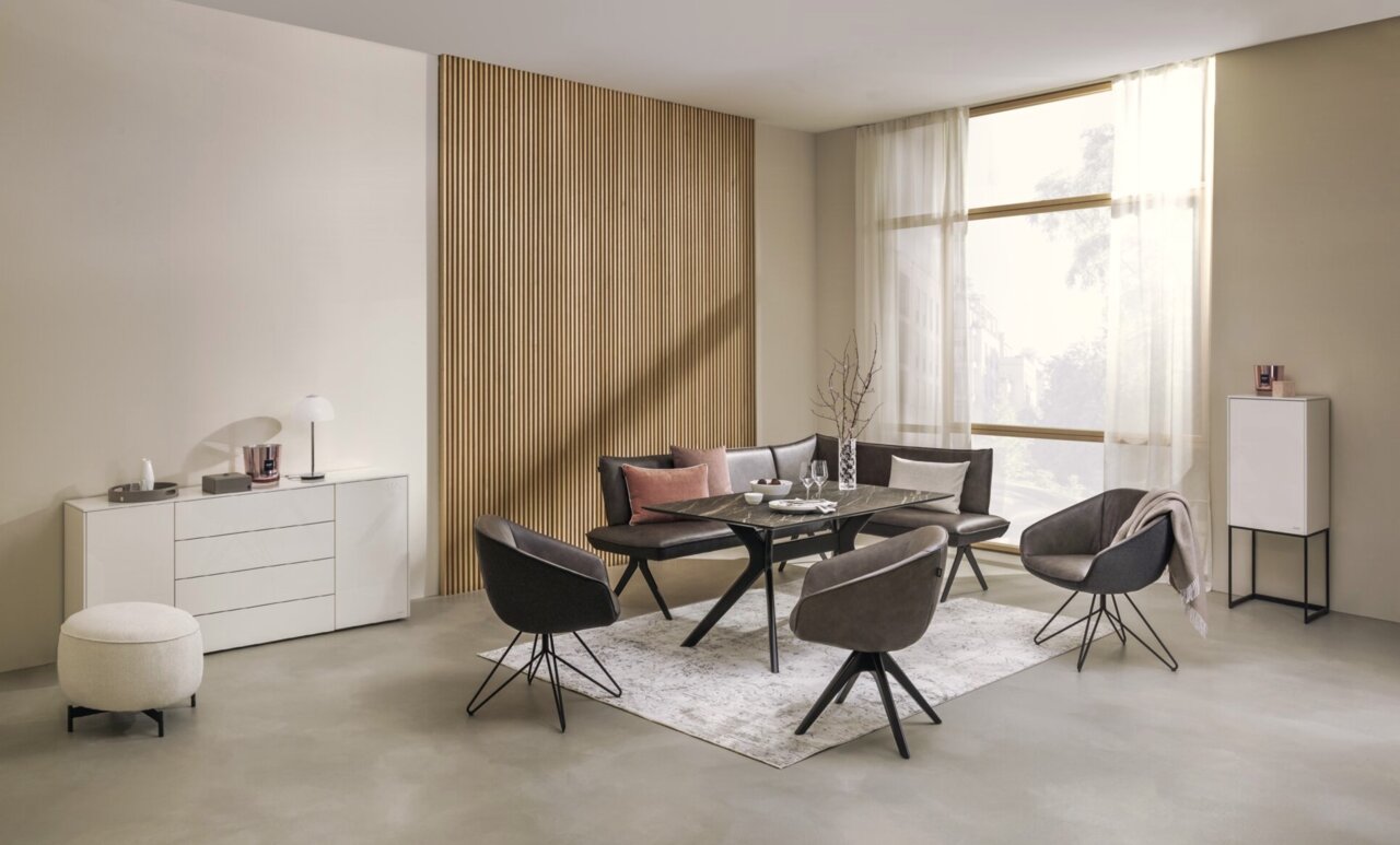 Moderner Esstisch mit schwarzer Tischplatte und eleganten Stühlen in einem stilvoll eingerichteten Raum, seitliche Perspektive.