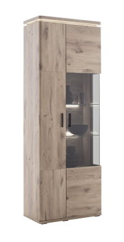 Hoge vitrinekast in lichte eikenlook met glazen vitrine en ledverlichting, zwarte handgrepen, vrijstaand tegen een witte achtergrond, schuin aanzicht van linksvoor