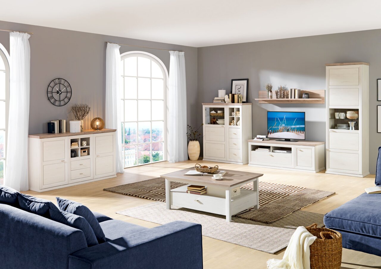 Moderne woonwand met dressoir, salontafel en decoratieve elementen in een lichte woonkamer met grote ramen, zijaanzicht.