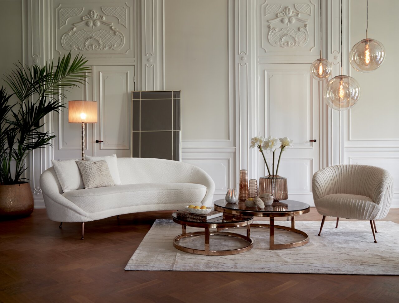 Elegante Hängeleuchte mit drei kugelförmigen Glaskörpern in einem stilvollen Wohnzimmer, seitliche Perspektive.