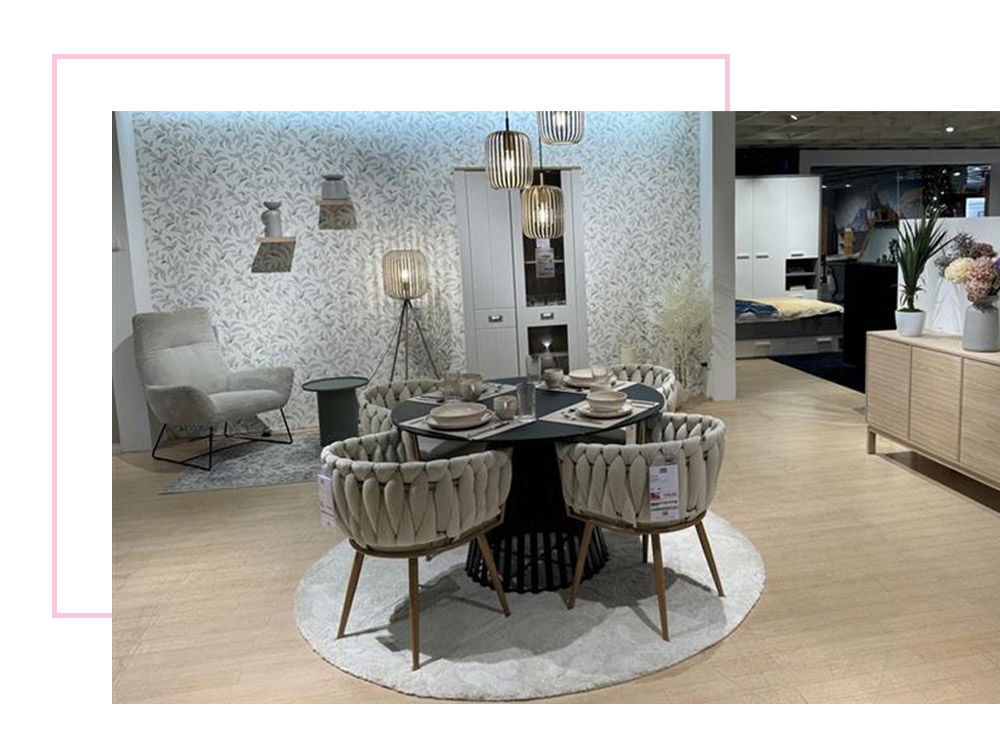 Gemütlicher Essbereich mit rundem Tisch und geflochtenen Stühlen.