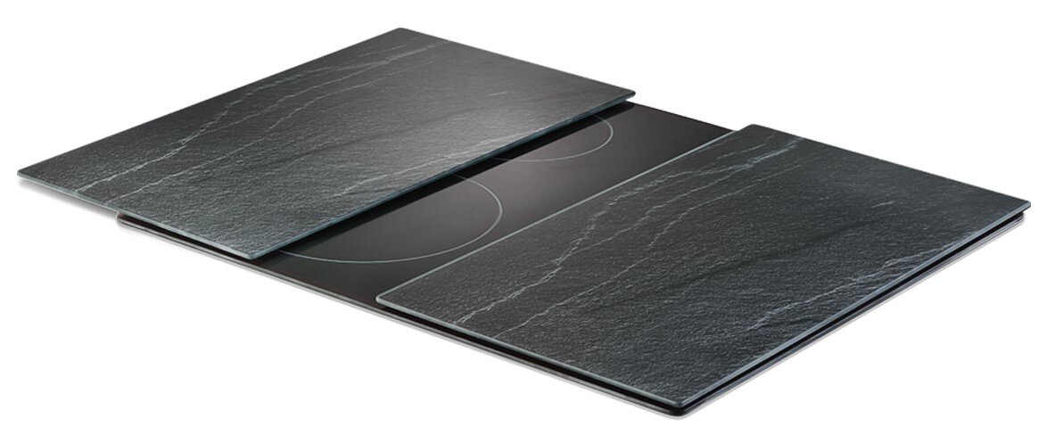 Zeller Present Glasschneideplatten-Set 2-tlg. Zwei schwarze Glasschneideplatten in Steinoptik, die auf einem Herd platziert sind, aus einer leicht seitlichen Perspektive fotografiert.