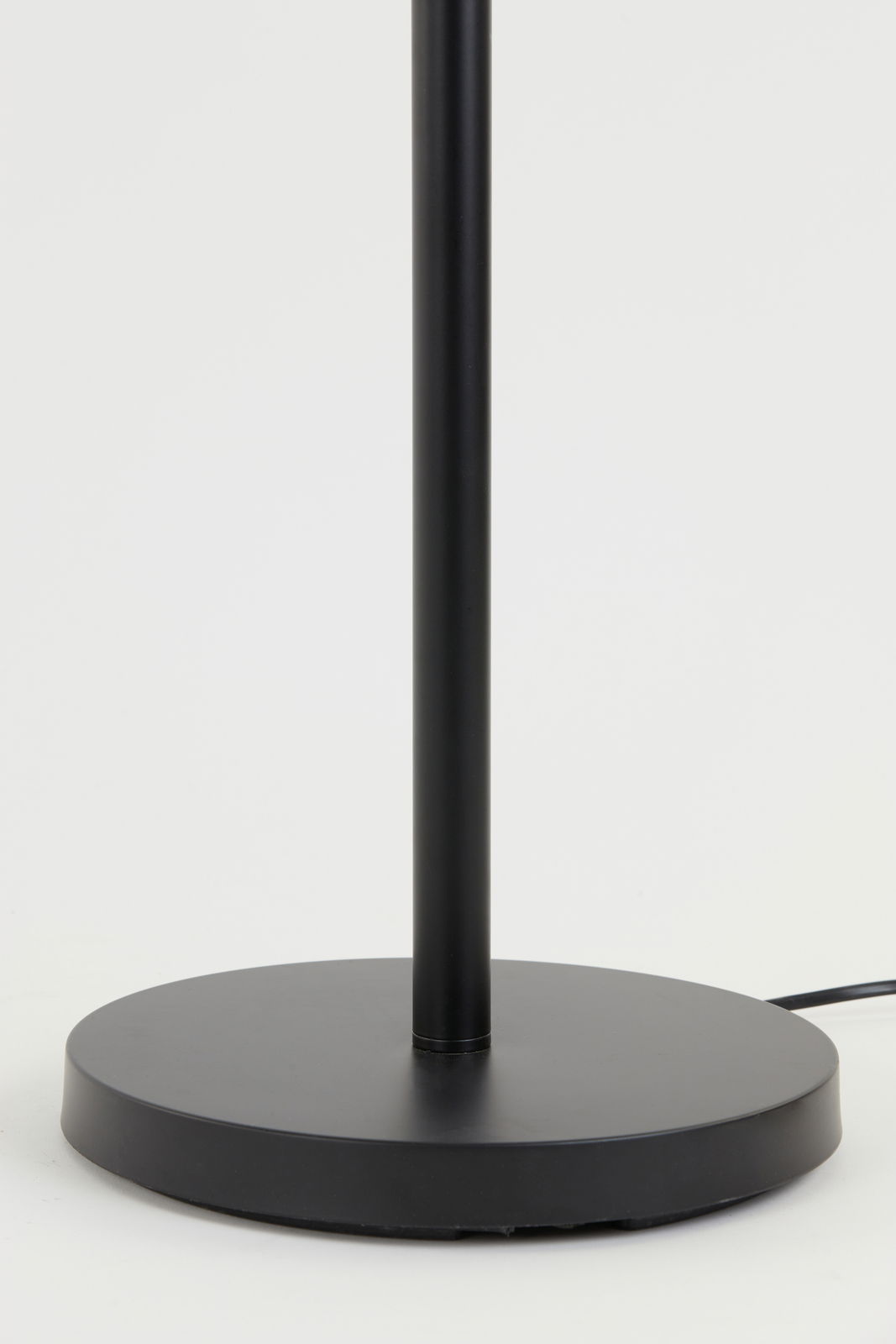 Nahaufnahme des Sockels einer schwarzen Stehleuchte mit rundem Fuß, seitliche Perspektive.