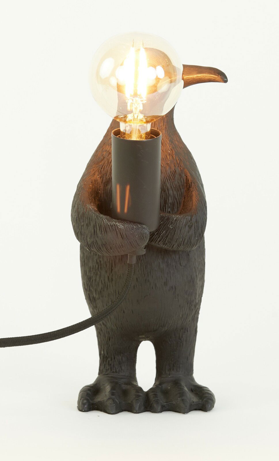 Tischleuchte in Form eines Pinguins, der eine Glühbirne hält, frontal betrachtet.