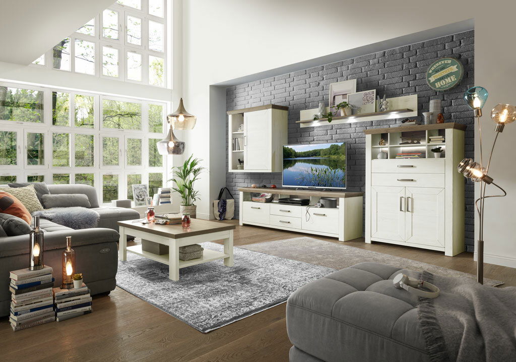 Wohnzimmer mit moderner Wohnwand in heller Holzoptik, bestehend aus Highboard, Hängeelement, Lowboard und Wandboard, mit dekorativer Beleuchtung und gemütlicher Atmosphäre, seitliche Perspektive.