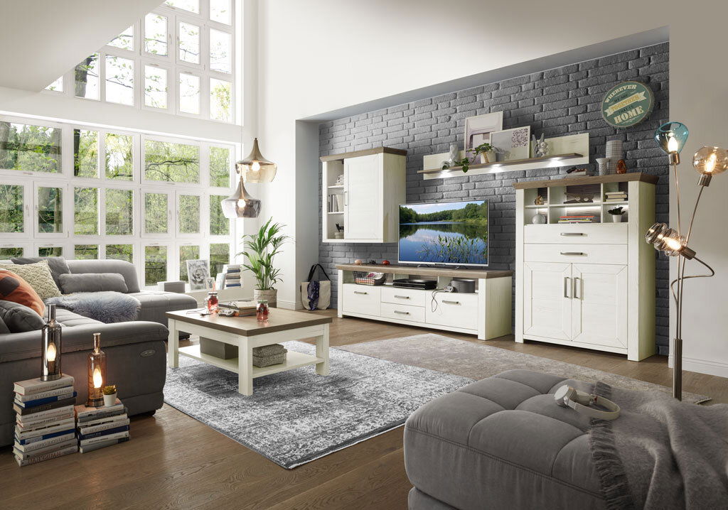 Wohnzimmer mit moderner Wohnwand in heller Holzoptik, bestehend aus Highboard, Hängeelement, Lowboard und Wandboard, mit dekorativer Beleuchtung und gemütlicher Atmosphäre, seitliche Perspektive.