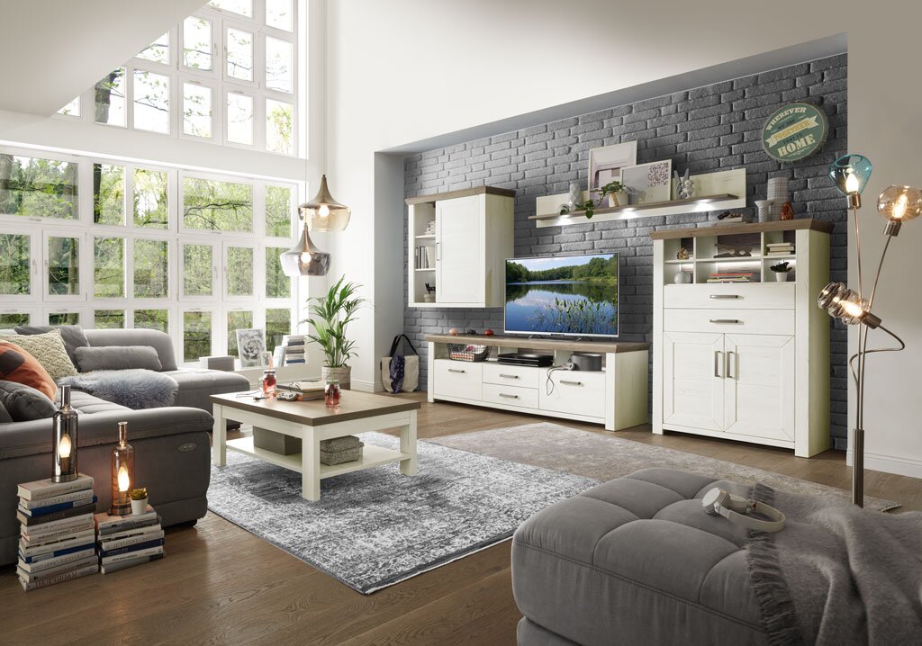 Wohnzimmer mit moderner Wohnwand in heller Holzoptik, bestehend aus Highboard, Hängeelement, Lowboard und Wandboard, mit dekorativer Beleuchtung und gemütlicher Atmosphäre, seitliche Perspektive.