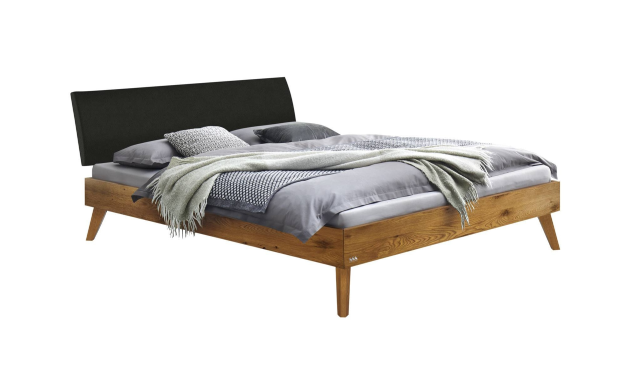 Holzbettgestell mit schwarzem Kopfteil, grauer Bettwäsche und Decken, seitliche Perspektive