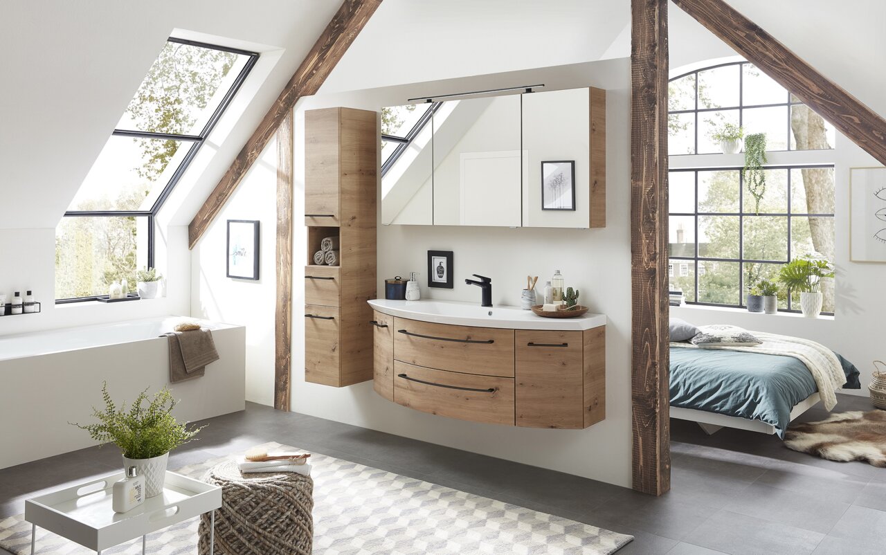 Sadena Hochschrank Türanschlag links PLAKA Moderner Hochschrank aus Holz in einem stilvollen Badezimmer mit Dachschräge, seitliche Perspektive.