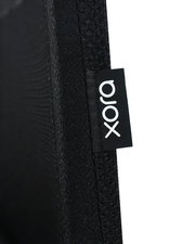 Nahaufnahme eines schwarzen Stoffes mit einem Etikett der Marke 'xora', seitliche Perspektive.