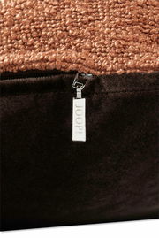 Nahaufnahme einer Zierkissenhülle mit grober Textur in Braun und einem silbernen Reißverschluss mit der Aufschrift 'JOOP!'