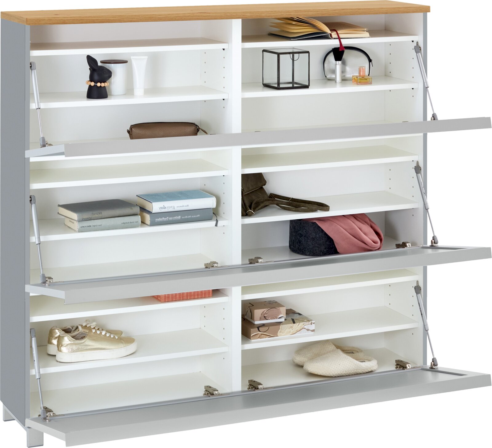 Weißes Schuhregal/Sideboard mit Holzplatte und drei nach unten klappbaren Fronten, geöffnet mit mehreren Fächern und Gasdruckdämpfern, befüllt mit Schuhen und Accessoires, Frontansicht leicht schräg von oben