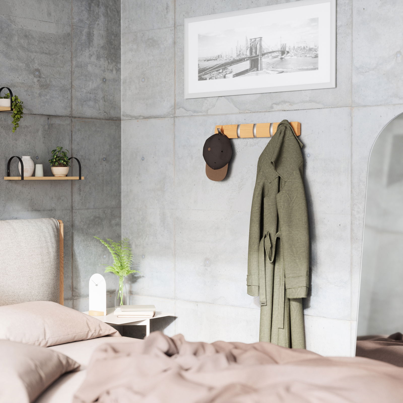 Wandgarderobe aus Holz mit mehreren Haken, an der eine grüne Jacke und eine braune Kappe hängen, in einem modernen Schlafzimmer mit Betonwänden. Perspektive von der Seite.