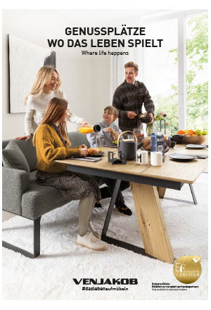 Eine Familie frühstückt an einem Holztisch in einem hellen Esszimmer mit großen Fenstern und Teppich.