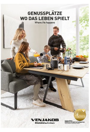 Eine Familie frühstückt an einem Holztisch in einem hellen Esszimmer mit großen Fenstern und Teppich.