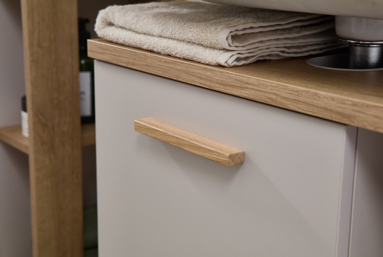 Close-up van een moderne wastafelonderkast met houten handgreep en handdoeken op het blad, zijaanzicht