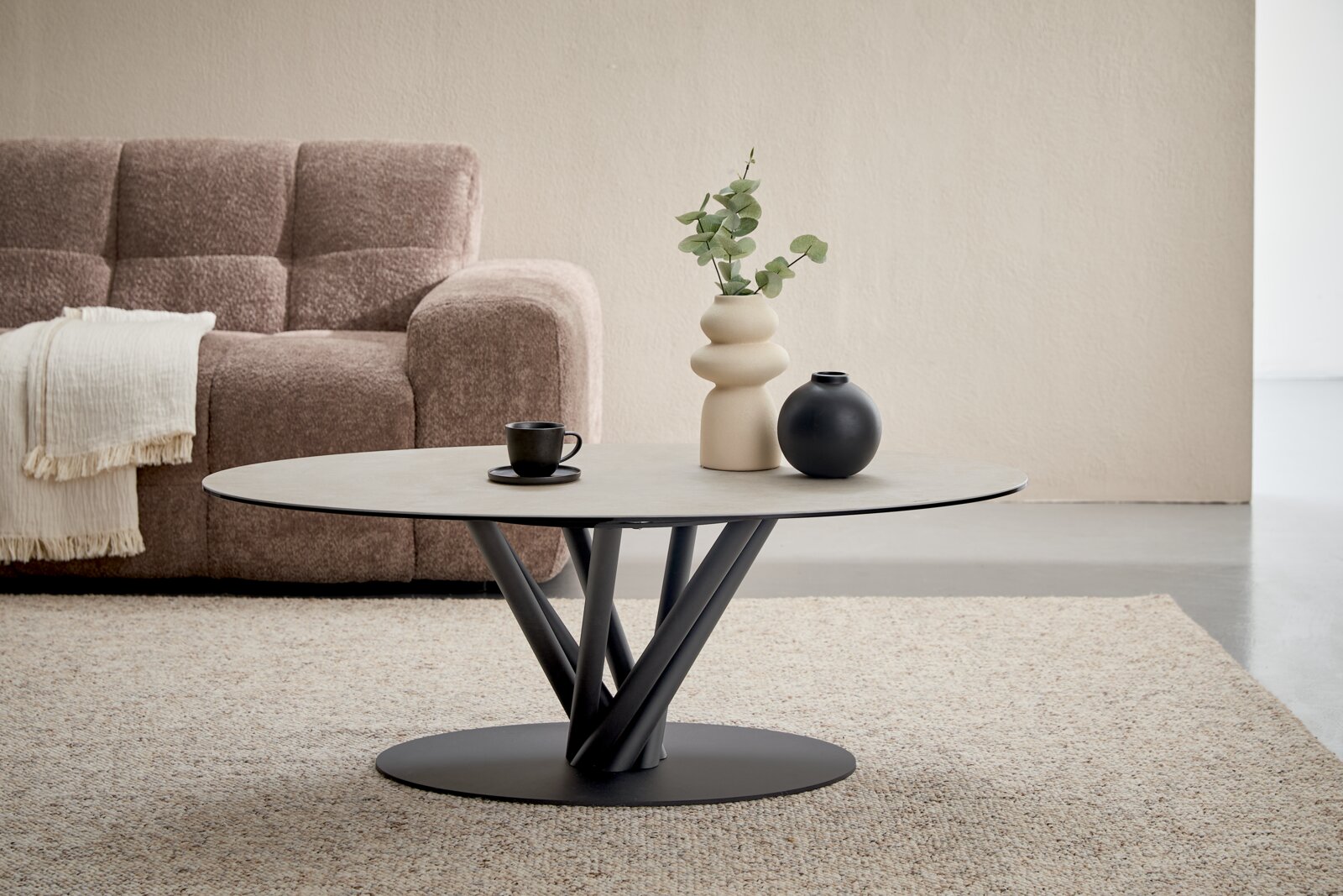 Belluti Couchtisch GIULIETTA Moderner ovaler Couchtisch mit heller Tischplatte, schwarzem Metallgestell in skulpturaler Ast-Optik und flachem Sockel, frontal aus leicht erhöhter Perspektive in einem stilvollen Wohnzimmer arrangiert