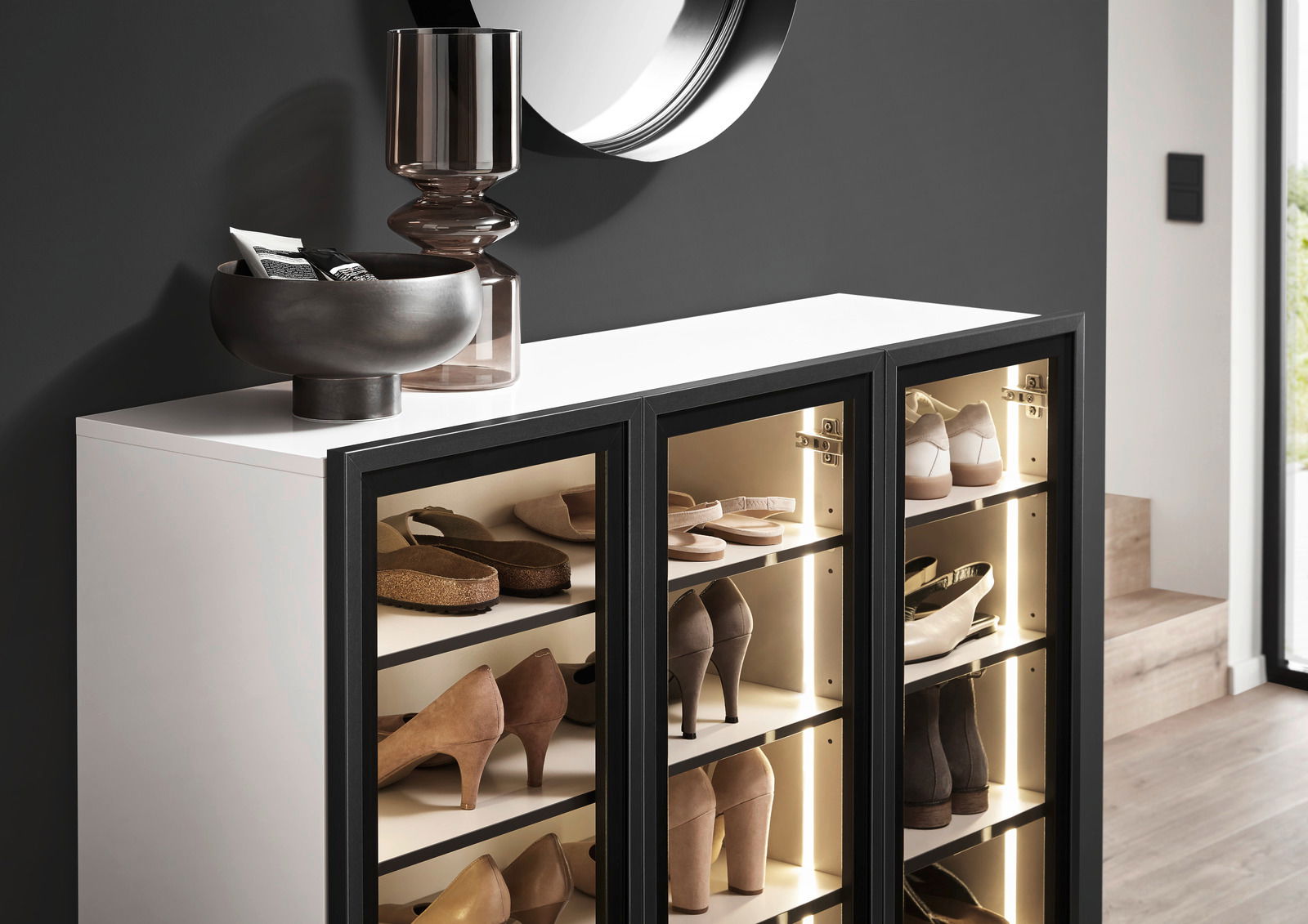 Schuhschrank-Vitrine mit Glastüren, gefüllt mit verschiedenen Schuhen, seitliche Perspektive