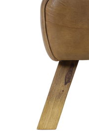 Nahaufnahme eines Hockers mit braunem Lederbezug und schrägem Holzbein, seitliche Perspektive.