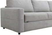 Detailansicht eines hellgrauen Stoffsofas aus schräger Frontperspektive mit breiter Armlehne, weichen Sitz- und Rückenkissen sowie kurzen schwarzen Füßen