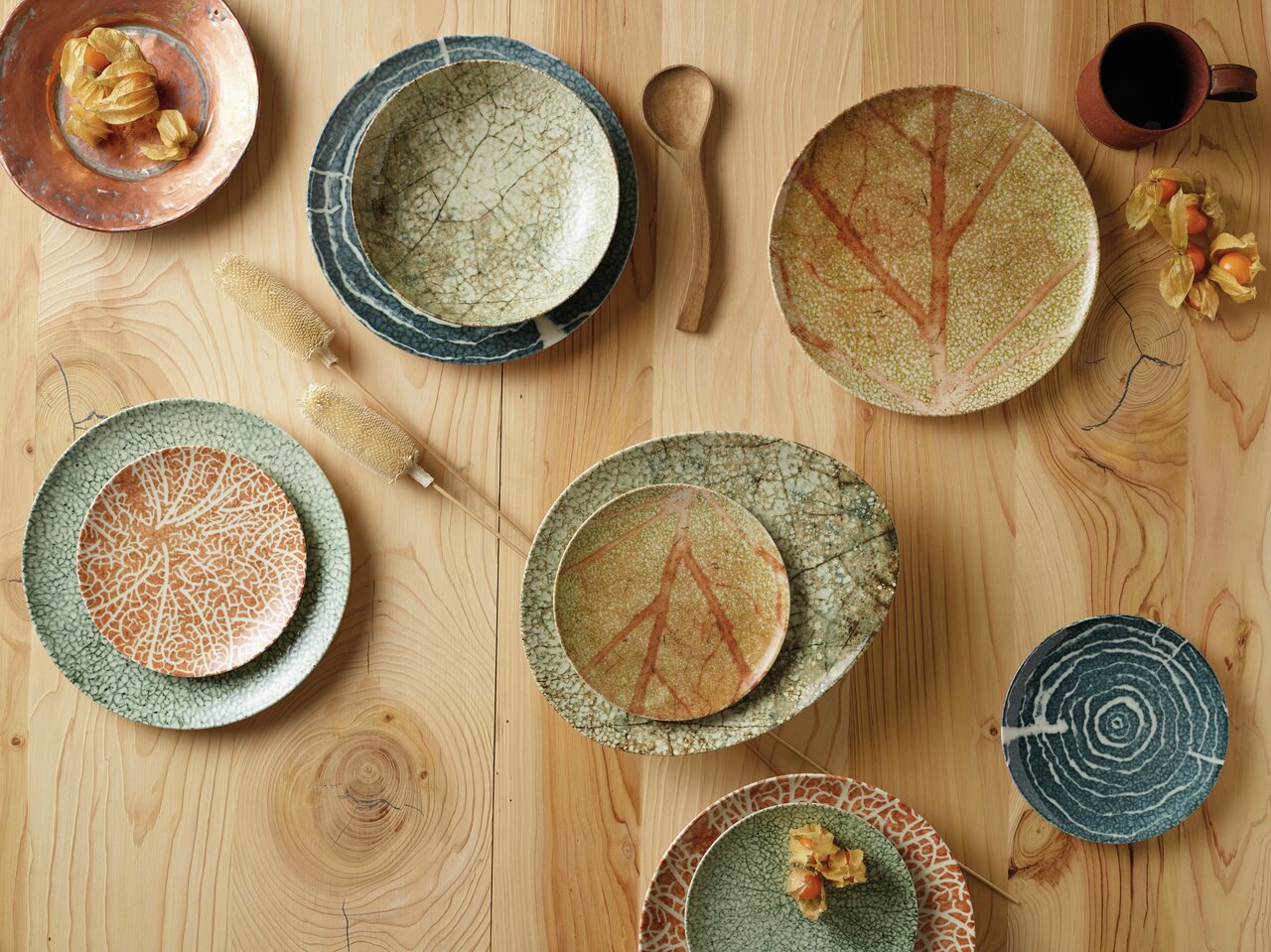 Arthur Krupp Servies Nature Essence, 12-delig Vogelperspectief op een servies met natuurlijke patronen en aardse kleuren op een houten tafel.