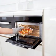 Rechteckige Glasform mit 0,45 L Fassungsvermögen, gefüllt mit buntem Gemüse, wird aus einem modernen Backofen entnommen. Seitliche Perspektive.