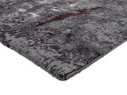 Nahaufnahme eines modernen Teppichs in Grautönen mit abstraktem Muster, perspektivisch von der Seite aufgenommen.