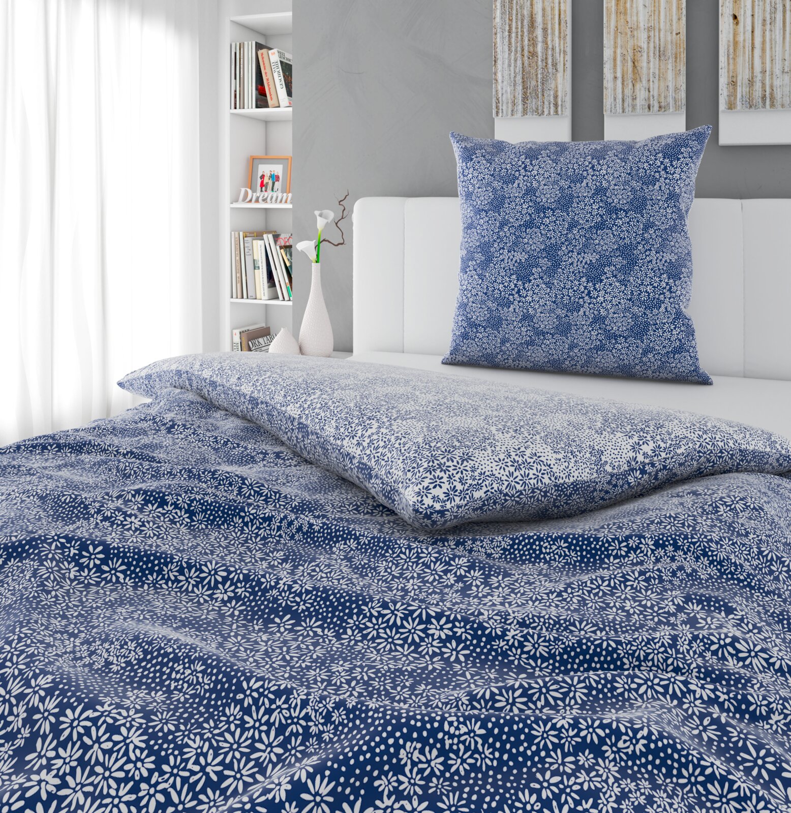 Blau-weiße Bettwäsche mit kleinem Blumenmuster, Decke und Kissen auf einem weißen Bett im hellen Schlafzimmer, Perspektive: leicht von oben und frontal auf das Bett