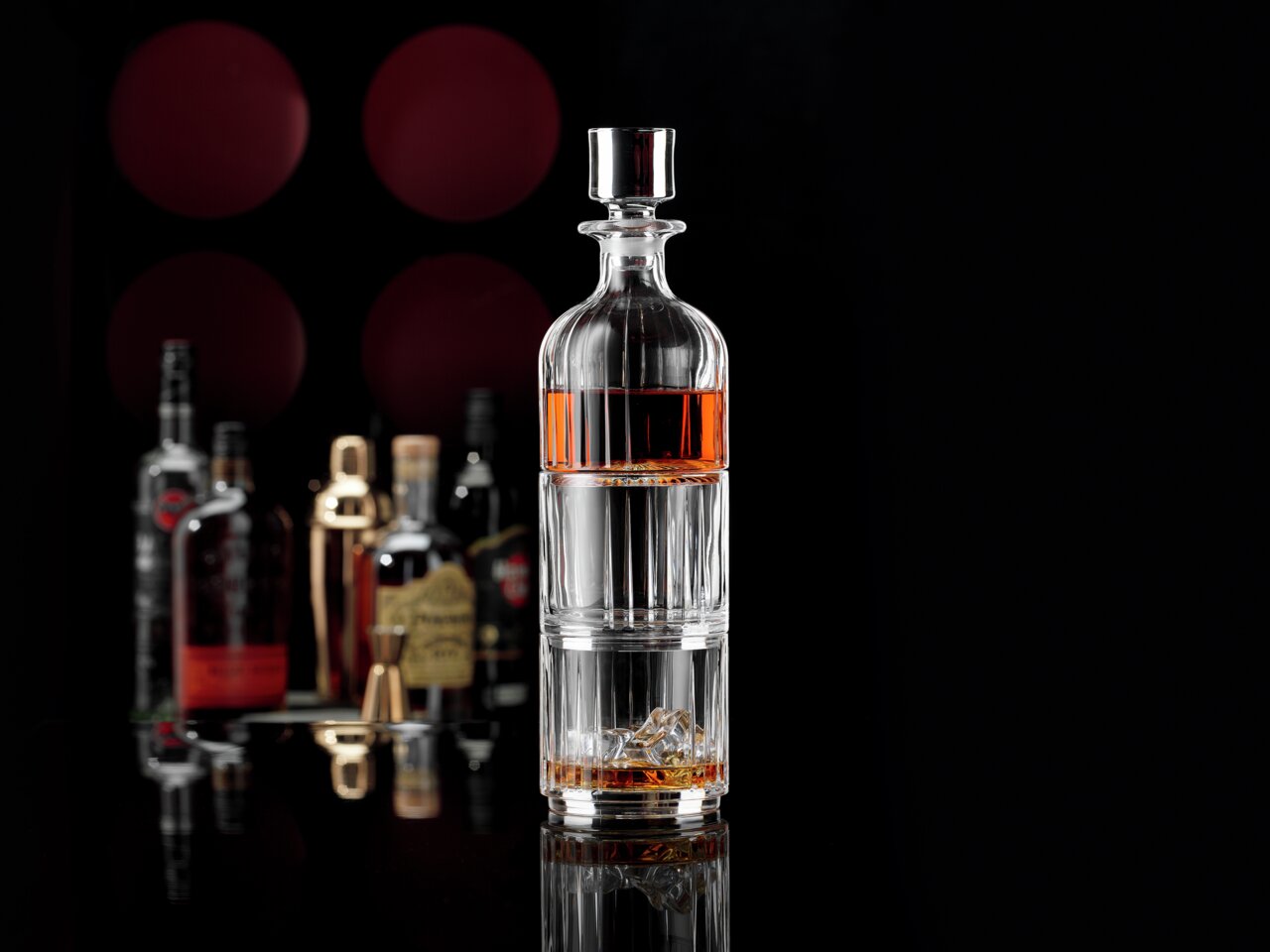 Elegante whiskyset met op de voorgrond een stijlvolle karaf, omringd door verschillende flessen op de achtergrond, gezien vanuit een zijdelingse hoek.