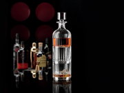 Elegante whiskyset met op de voorgrond een stijlvolle karaf, omringd door verschillende flessen op de achtergrond, gezien vanuit een zijdelingse hoek.