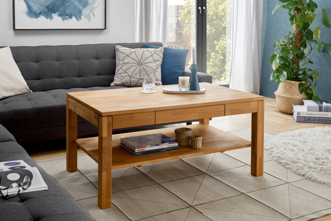 Holz-Couchtisch in einem modernen Wohnzimmer, frontal fotografiert, mit Dekorationen und einem Regal darunter.