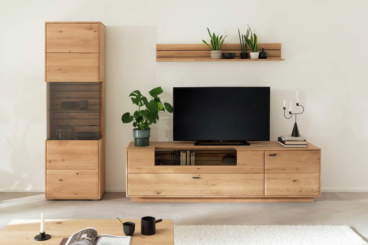 Linea Natura Wandkombination GEORGIA Moderne Wandkombination aus Holz mit TV-Schrank, Regal und Vitrine, frontal betrachtet. Dekoriert mit Pflanzen und Kerzenhalter.