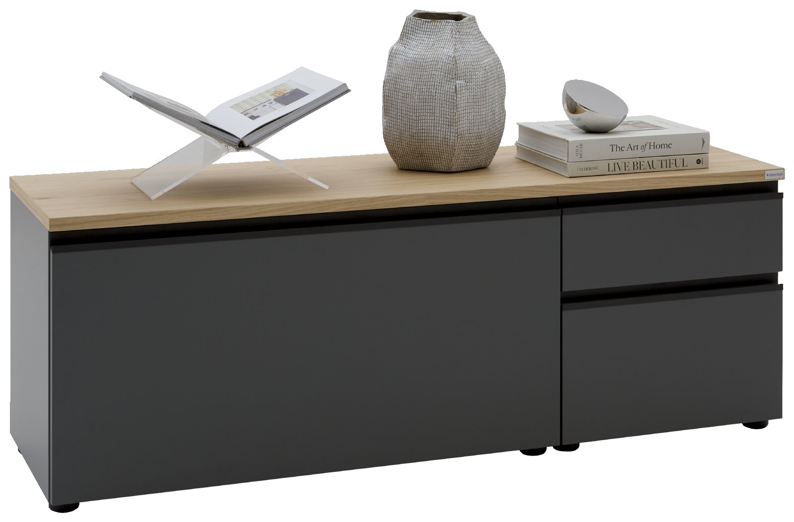 Modernes Lowboard/TV-Board in mattem Schwarz mit heller Holzplatte, zwei Türen links und zwei Schubladen rechts frontal in leichter Seitenperspektive von links fotografiert, dekoriert mit Buchständer, Vase und Bücherstapel.