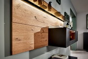 Moderne wandcombinatie met houten bekleding en zwarte kasten, zijaanzicht
